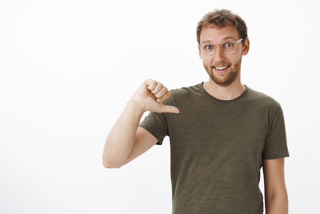 Free photo portrait of ambitious good-looking male coworker in dark-green t-shirt pointing at himself while volunteering to be candidate smiling joyfully