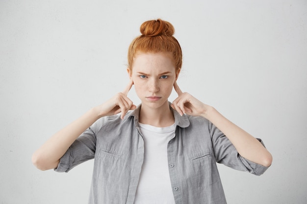 Free photo portrait of angry and annoyed young female frowning and plugging her ears with fingers can't stand loud noise or ignoring stressful unpleasant situation or conflict. negative human emotions