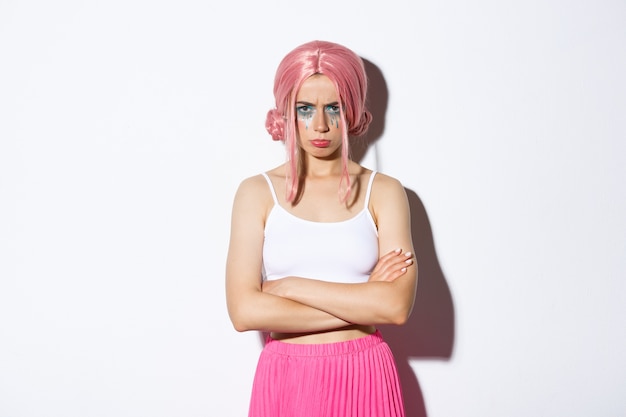 Portrait of angry cute girl with pink wig and glamour makeup, cross arms on chest and sulking mad