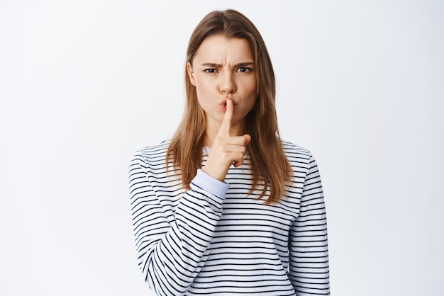 Free Photo portrait of angry woman frowning shushing at camera and tell to be quiet need silence scolding someone for being loud standing against white background