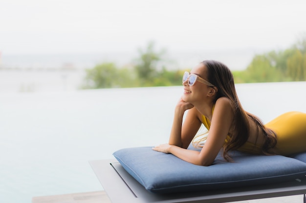 Free photo portrait asian beautiful young woman happy smile relax around outdoor swimming pool in holiday vacation