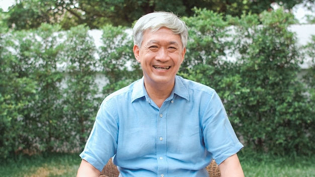 Free photo portrait asian chinese senior man feeling happy smiling at home. older male relax toothy smile looking while lying in the garden at home in the morning concept.