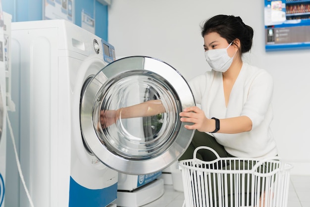 Free photo portrait asian female wear virus protecting mask in spread of covid19 washing in blue color interior laundry shop in condoiminuim city new normal lifestyle