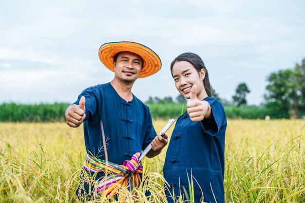 Portrait Asian Middle aged man wearing straw hat and loincloth write on clipboard with young woman farmer