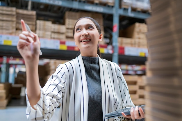 Free Photo portrait of asian woman business owner using digital tablet checking amount of stock product inventory on shelf at distribution warehouse factorylogistic business shipping and delivery service