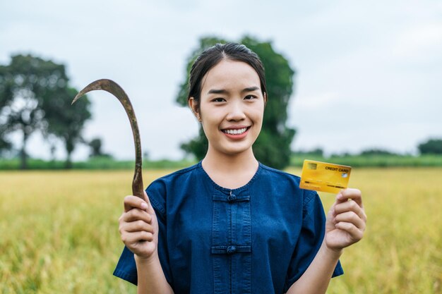 Portrait of asian young farmer woman showing credit card on rice field