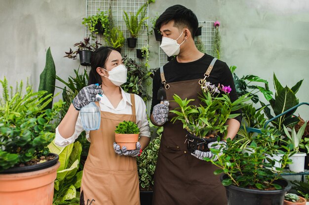 Portrait asian young gardener couple wearing apron use garden equipment and help to take care the houseplant in shop