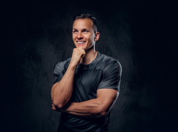 Portrait of an athletic fitness male dressed in a sportswear over grey vignette background.