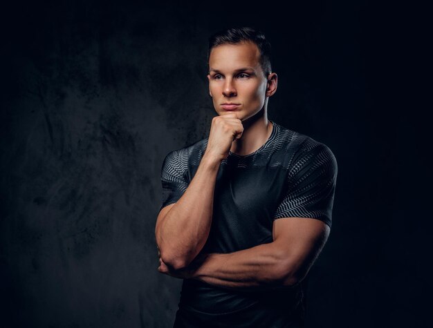 Portrait of an athletic fitness male dressed in a sportswear over grey vignette background.