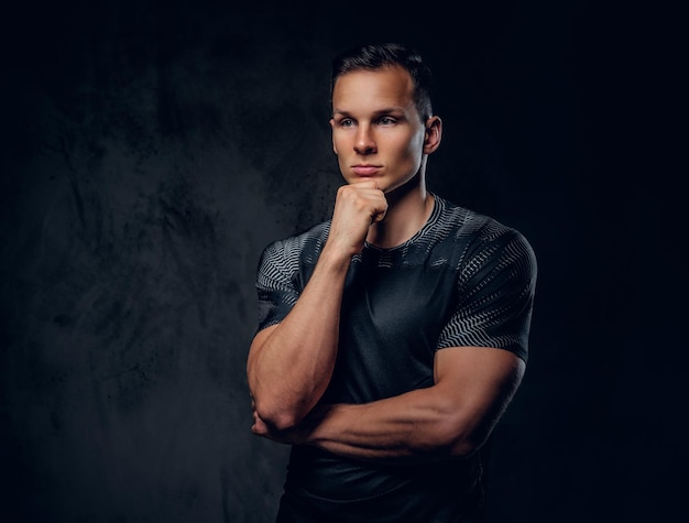 Portrait of an athletic fitness male dressed in a sportswear over grey vignette background.