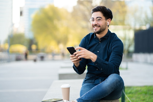 Portrait of an athletic man using his mobile phone on a break from training while sitting on concrete stairs