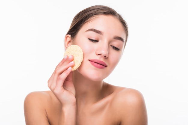 Portrait of attractive caucasian smiling woman cleaning her face isolated on white wall