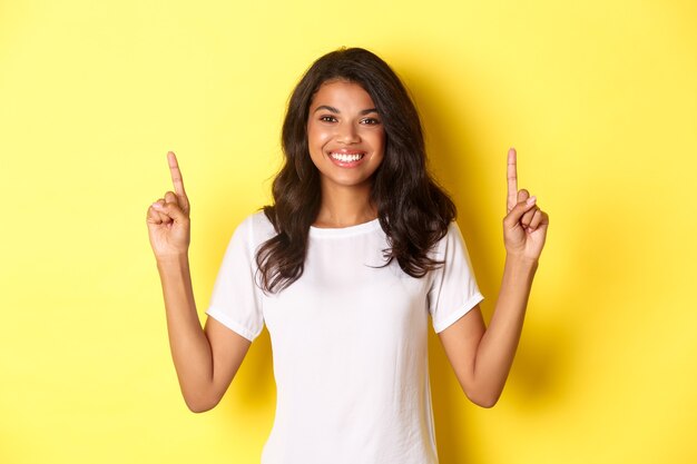 Portrait of attractive and confident africanamerican female model wearing white tshirt pointing