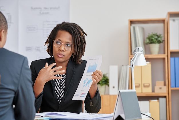 Portrait of  attractive Cuban woman presenting the statistical information to her unrecognizable boss