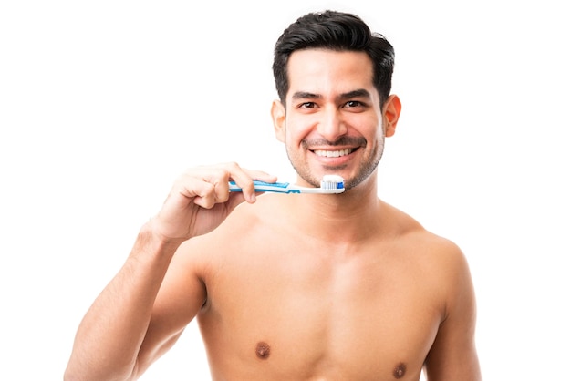 Portrait of attractive man holding toothbrush while smiling in studio