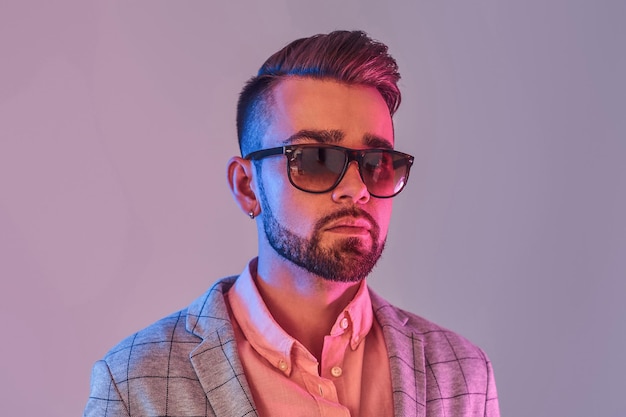 Portrait of attractive pensive man in checkeret blazer and sunglasses. Red and blue lights.