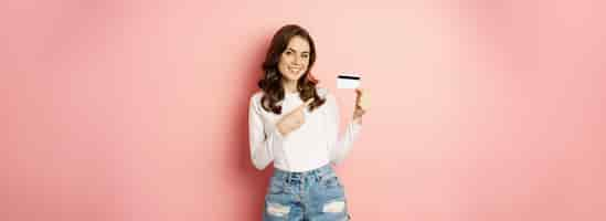 Free photo portrait of attractive smiling woman showing credit card recommending app store with discounts stand