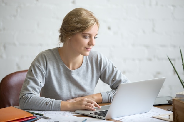 Portrait of attractive student girl at the desk with laptop