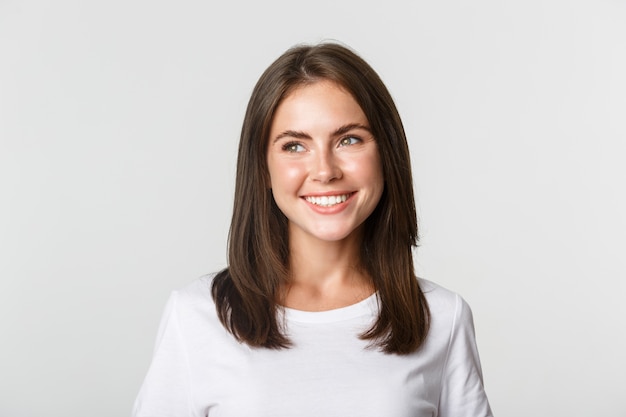 Portrait of attractive thoughtful girl smiling and looking left, white.