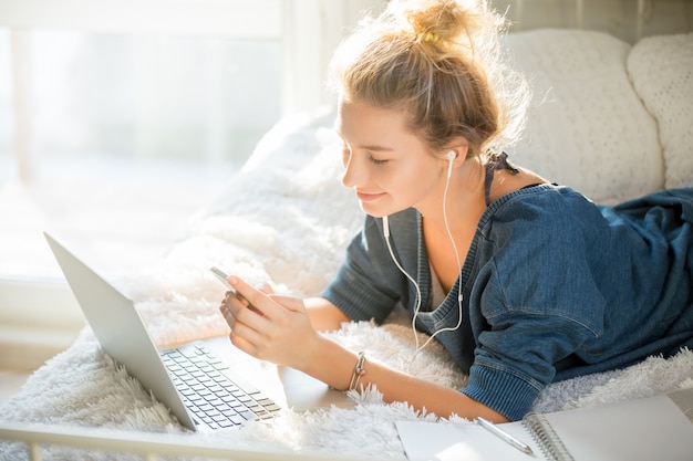 Free photo portrait of an attractive woman lying on bed with laptop