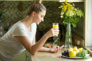 Free photo portrait of an attractive woman with juice and phone