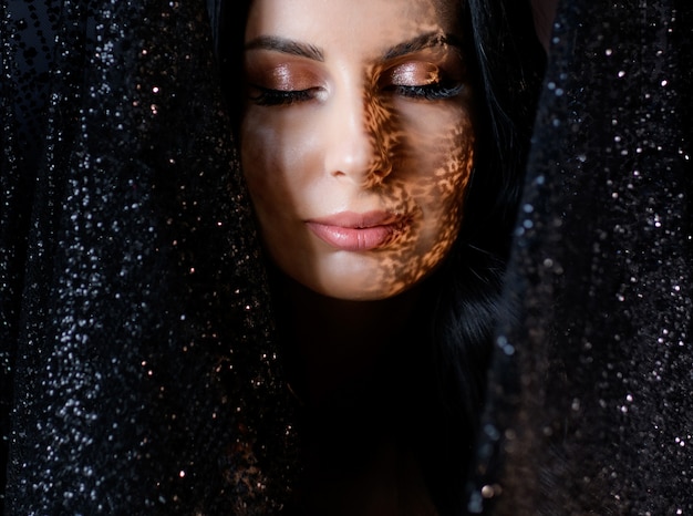 Free Photo portrait of attractive young girl with tender make up and shadow on the face surrounded with black glitter lace