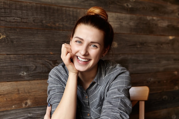 Free photo portrait of attractive young redhead caucasian woman dressed casually posing isolated against wooden wall