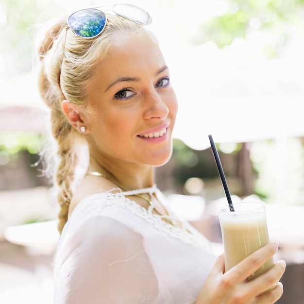 Portrait of a attractive young woman holding glass of latte macchiato