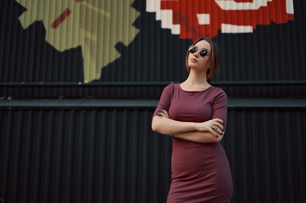 Portrait of attractive young woman posing against dark wall