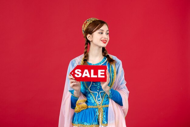 Portrait of azeri woman in traditional dress holding sale nameplate on red