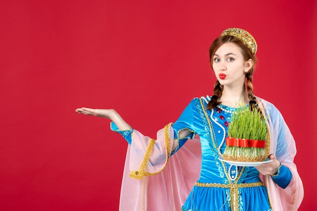 Portrait of azeri woman in traditional dress holding semeni on red