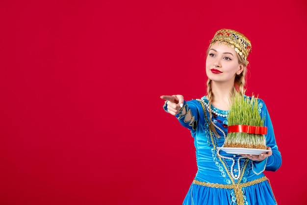 Free photo portrait of azeri woman in traditional dress with green semeni on red background concept ethnic dancer spring