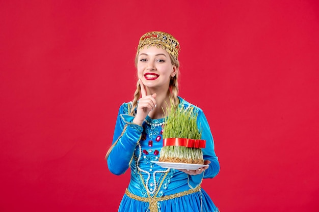 Free Photo portrait of azeri woman in traditional dress with semeni studio shot red background holiday concept spring novruz