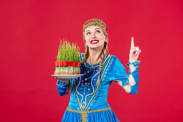 Free Photo portrait of azeri woman in traditional dress with semeni studio shot red background spring holiday ethnic novruz concept