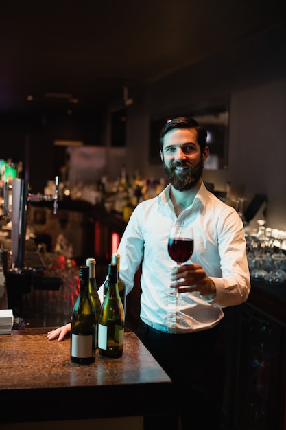 Portrait of Bartender holding glass of red wine