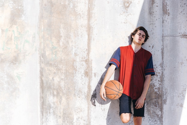 Portrait of a basketball player leaning on wall