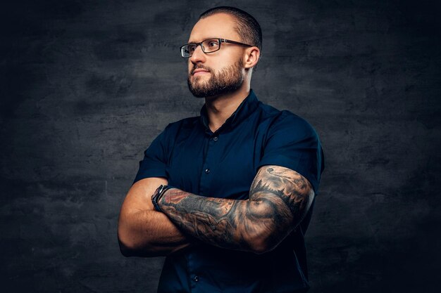 Portrait of bearded male in sunglasses with tattoo on his arm.