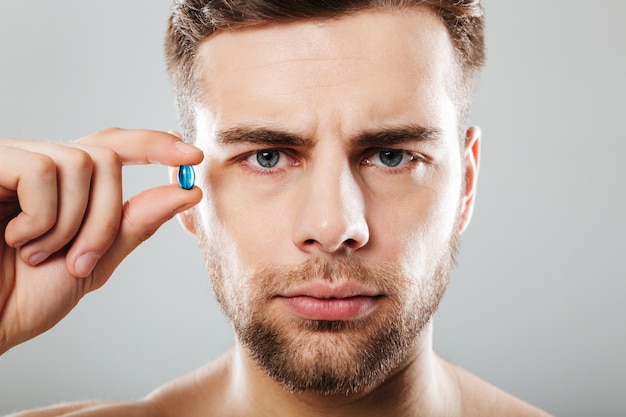 Portrait of a bearded man holding capsule at his face