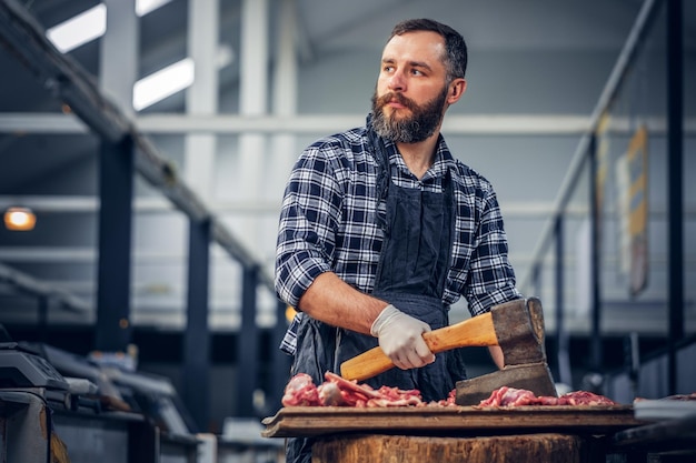 Free photo portrait of a bearded meat man dressed in a fleece shirt holds an axe and fresh cut meat.