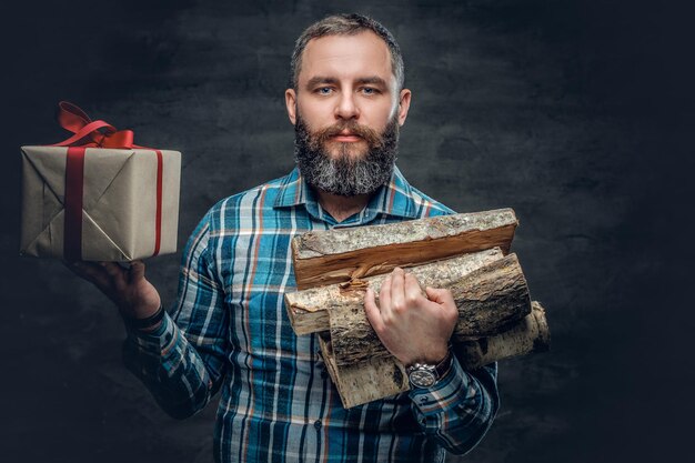 Portrait of bearded middle age male holds fire woods and Christmas gift box.