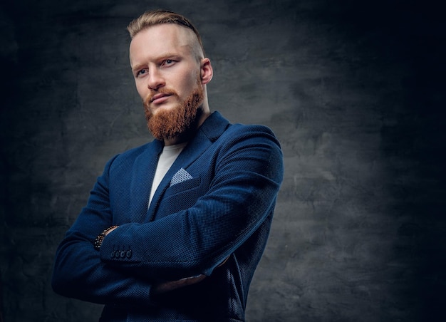 Free photo portrait of bearded redhead hipster male dressed in a blue jacket over grey background.