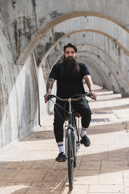 Portrait of a bearded young man riding the bicycle in arches