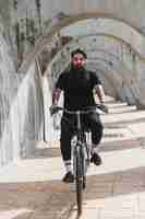 Free photo portrait of a bearded young man riding the bicycle in arches