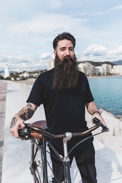 Portrait of a bearded young man with his bicycle