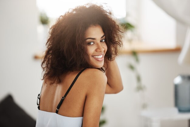 Portrait of beautiful african woman smiling. Bedroom background.