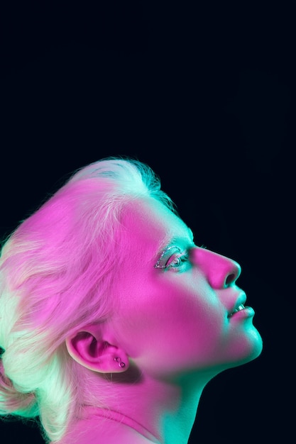 Portrait of beautiful albino girl isolated on dark studio in neon light