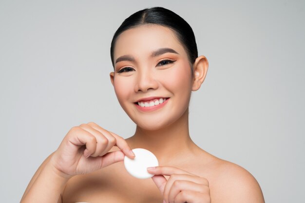 Portrait of Beautiful Asian woman holding foundation or cushion sponge puff