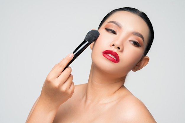 Portrait of Beautiful Asian woman holding makeup blusher brush