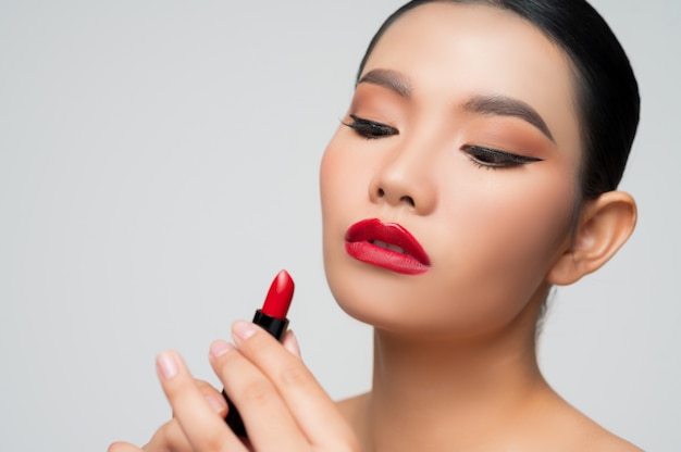 Portrait of Beautiful Asian woman with lipstick in hand