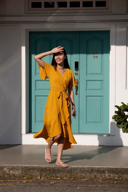 Portrait of beautiful asian woman in yellow dress posing outdoors in the city